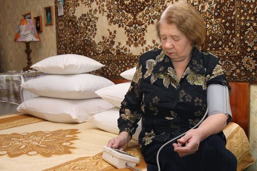 The elderly woman measures to itself a blood pressure