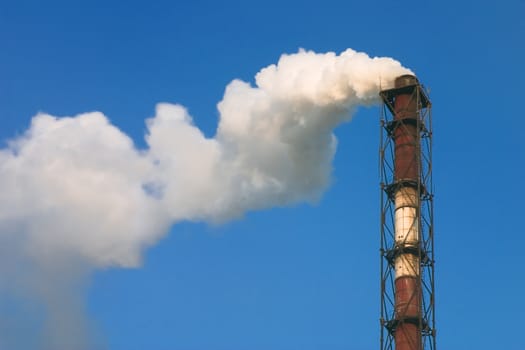 Smoke from a factory pipe on a background of the blue sky