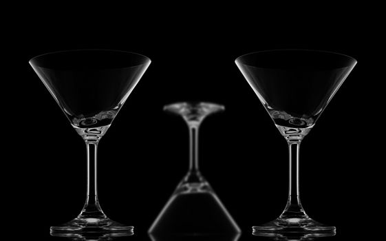 Two Sharp Cocktail glasses and one blur upside down on black background and reflection