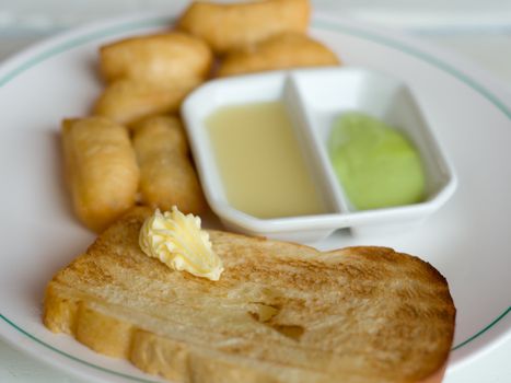 Bread with butter and Deep fried Dough Sticks Custard condensed milk on white table