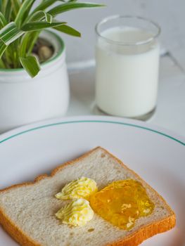 Bread butter jam on white plate with glass of milk