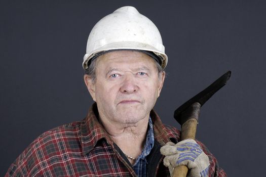 Portrait of an active senior man lumberjack or logger ready to work in the forest with scratched up hard hat, axe, plaid shirt and gloves, great details.