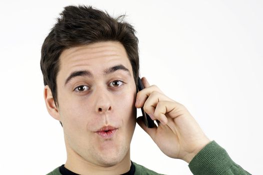 Portrait of handsome young man or student making a funny surprised face as he speaks on his cell phone or mobile, great details.