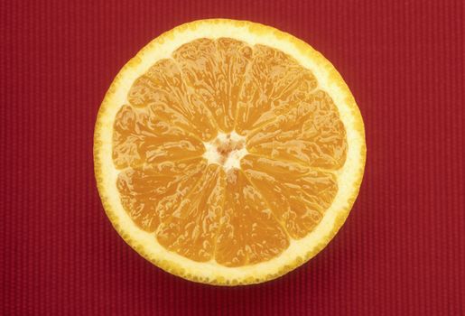 An orange sliced in half on a red place mat