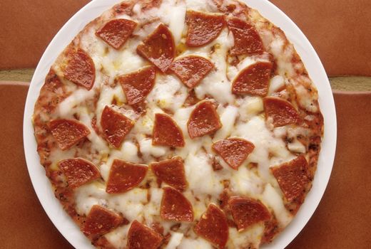 Delicious pepperoni and cheese pizza plate on kitchen tile

