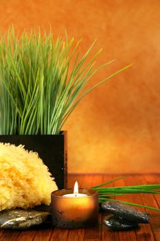 Spa setting with candle, sponge and herb grass