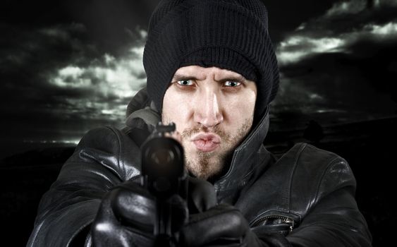 Portrait of an undercover agent or delinquent dressed in black leather and balaclava hat firing handgun in the camera.

Studio shot.