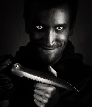 Black and white shot of a man with a knife hysterically smiling.