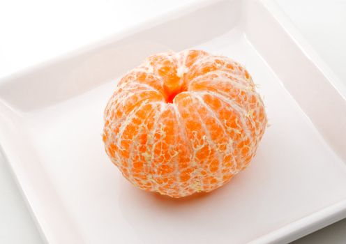 Fresh tangerine on a white plate, studio shot.