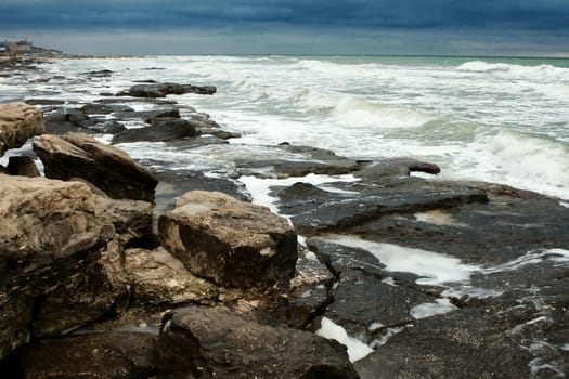 Deserted rocky shoreline with lines of white breakers pounding the rocks