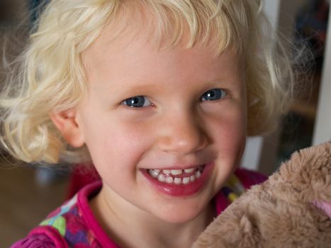 Smiling beautiful little girl with her teddy bear just before bed time