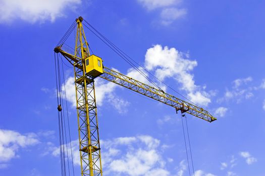 Construction crane against the background a blue sky with lightweight clouds