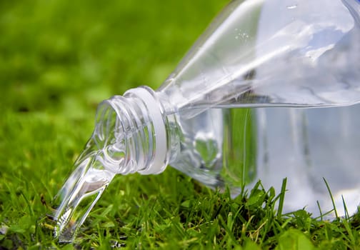  an opened  bottle of water upside down in the grass