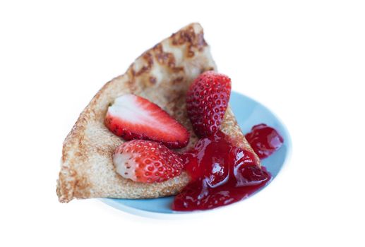 Pancake with strawberries and jam on a blue saucer.