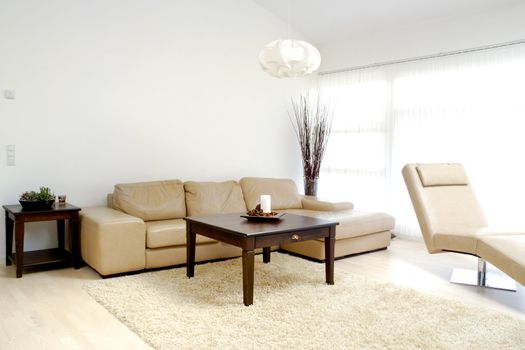 A modern living room with table, sofa and armchair.