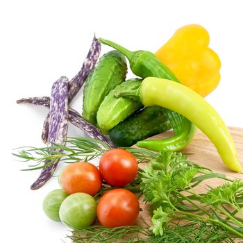 Tomatoes, two sharp pepper, parsley, dill, tarragon on a wooden board round, cucumbers, bell peppers, three green beans isolated on white background