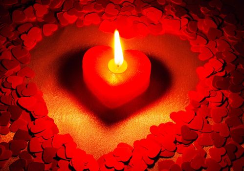 Burning heart shaped candle over red background