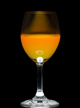 Orange juice in wine glass on black background