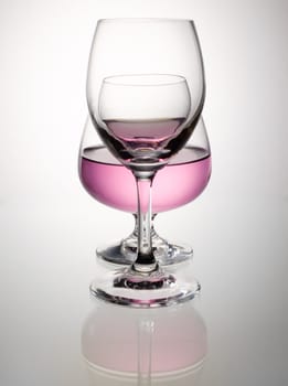 Pink wine in brandy glass overlap and reflection on white table