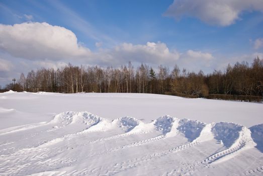 Snow pushed into piles in the park. Winter backdrop. Cloudy sky.