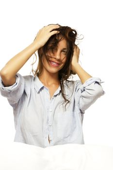 happy woman in pajamas playing with her hair on white background