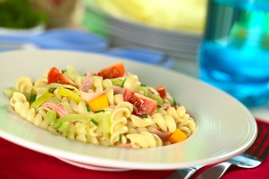 Pasta salad with leek, cherry tomato, yellow bell pepper and ham garnished with chives (Selective Focus, Focus on the tomato in the front)