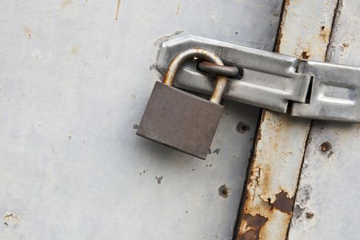 Close-up of padlock on old metal door.