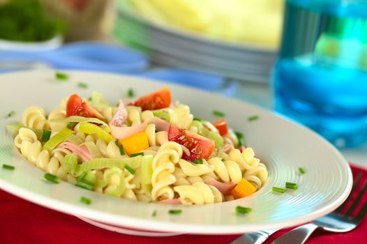 Pasta salad with leek, cherry tomato, yellow bell pepper and ham garnished with chives (Selective Focus, Focus on the tomato in the front)