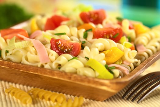 Pasta salad with leek, cherry tomato, yellow bell pepper and ham garnished with chives (Selective Focus, Focus on the tomato in the front)