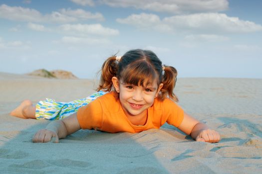 happy little girl lying on sand