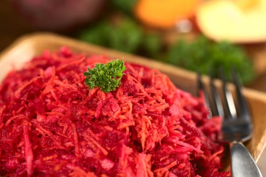 Fresh grated beetroot, carrot and apple salad garnished with a parsley leaf (Selective Focus, Focus on the front of the parsley leaf)