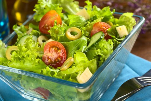 Fresh vegetable salad made of cherry tomato, cucumber, green olives and cheese (Selective Focus, Focus on the tomato half in the front)