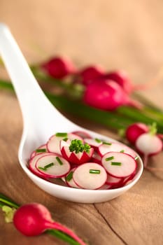 Fresh radish salad with chives (Selective Focus, Focus on the front of the parsley leaf and the radish garnish below)