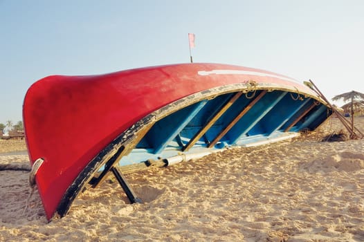 Turned over a red boat on a sandy beach