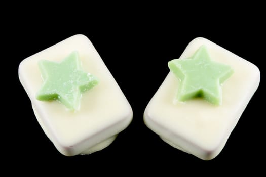 Two pastries of white chocolate with stars green isolated on a black background