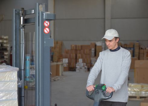 Good looking guy at forklift picking and moving packages in a warehouse