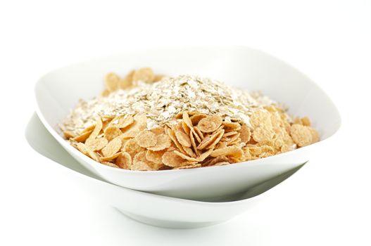Muesli and corn flakes in white plates on white background