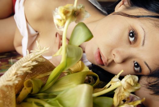 Sensual portrait of sorrowful lady laying with flowers