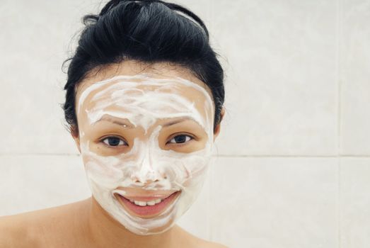 Smiling woman with moisturizing facial cream 