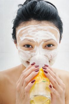 Drinking smiling woman with beauty mask