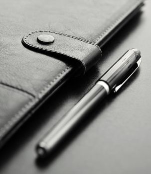 Close-up of a black personal agenda and with a pen with selective focus