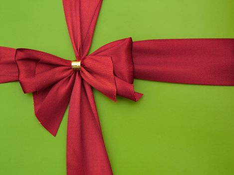 Bow of red satin ribbon on a green background