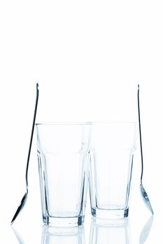 two empty latte macchiato glasses with standing spoons on white background