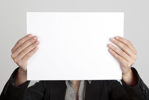 Woman showing a blank paper sheet in front of her head
