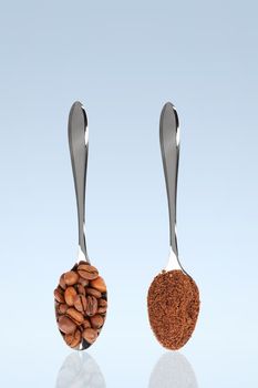coffee beans and grinded coffee on standing spoons with blue background