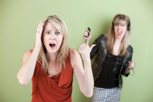Annoyed mom with daughter listening on headphones