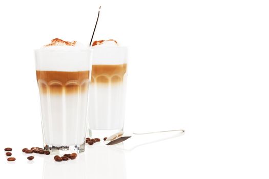 two glasses latte macchiato with coffee beans and chocolate powder on white background