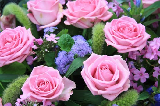 Floral arrangement with pink roses and purple and green decoration