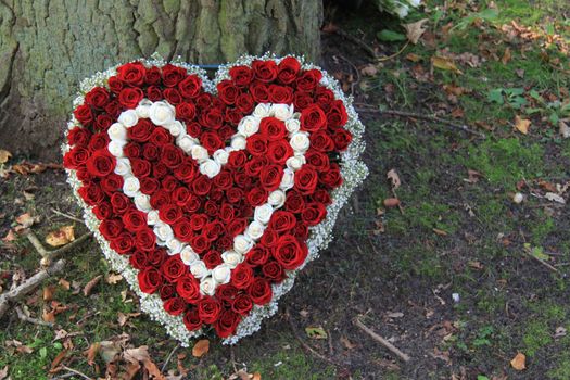 Sympathy flowers in a heart shape near a tree