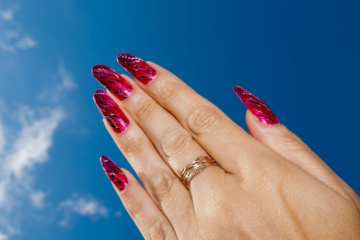 Manicured female hands against blue sky